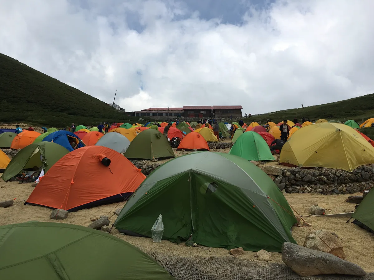 密集した色とりどりのテントと山小屋