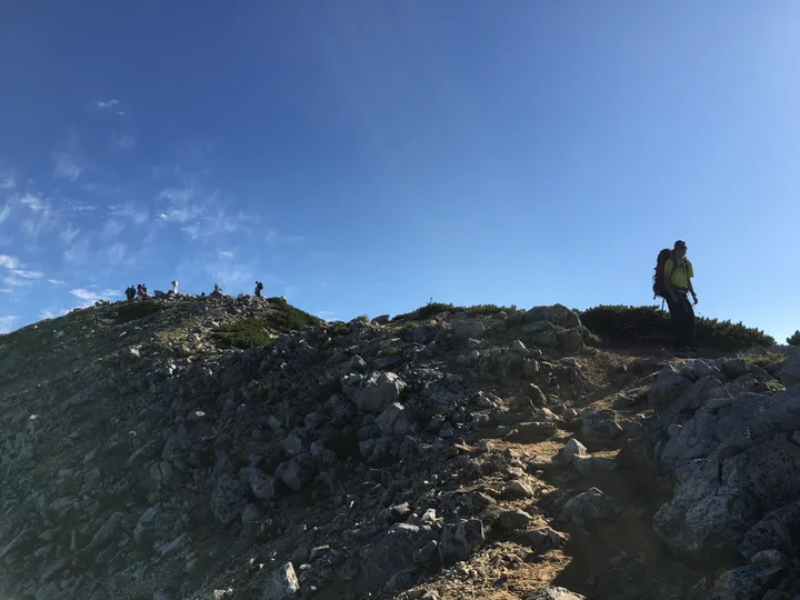 小さい岩の多い山を見上げる、頂上には人がたくさんいる